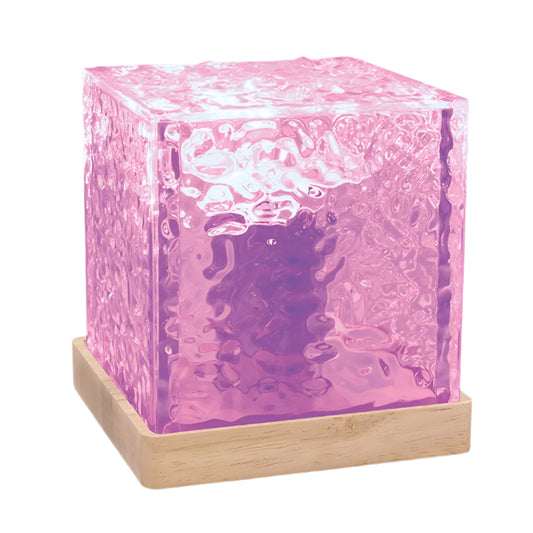 A purple LED cube lamp with a textured surface placed on a wooden base, illuminated to create a water wave effect.